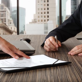 hand pointing to contract document on table