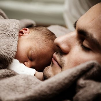 Baby sleeping in bed with father