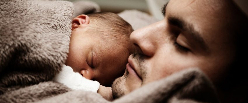 Baby sleeping in bed with father