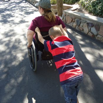 Child pushing woman in wheelchair