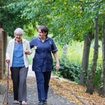 elderly woman walking with nurse