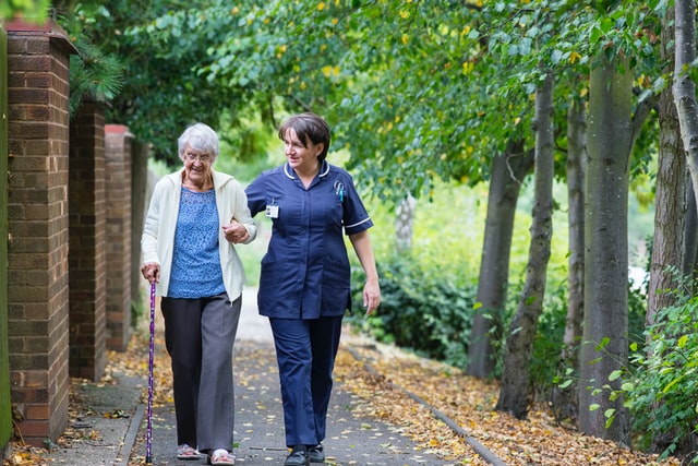 elderly woman walking with nurse