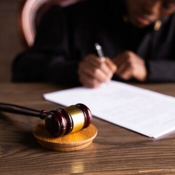 man signing document with gavel on table