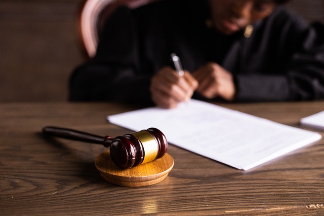 man signing document with gavel on table