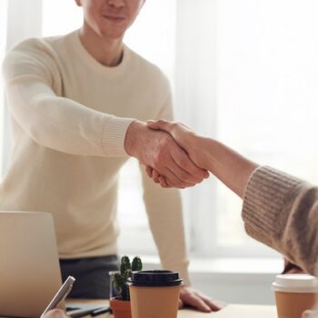 man and woman shake hands over desk