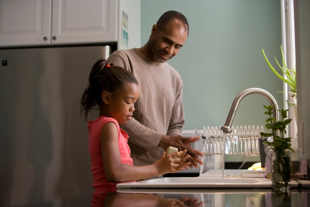 girl washing hands in kitchen with dad