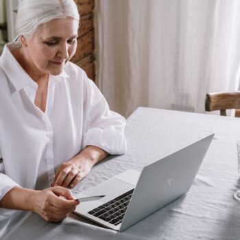 elderly woman using laptop with credit card