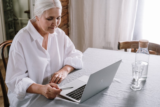 elderly woman using laptop with credit card