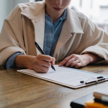 woman in jacket signing paperwork