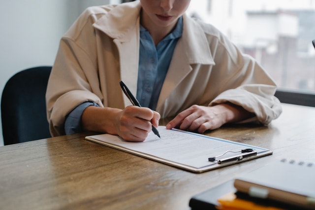 woman in jacket signing paperwork
