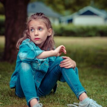 sad girl sitting by herself under tree