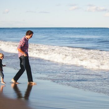 child and stepparent walking on beach