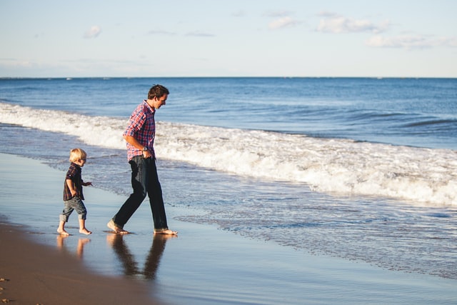 child and stepparent walking on beach