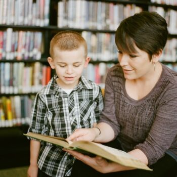 woman and boy in library with book