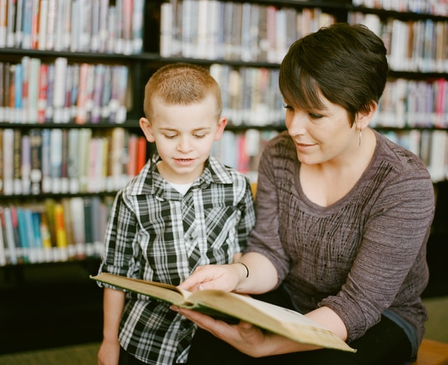 woman and boy in library with book