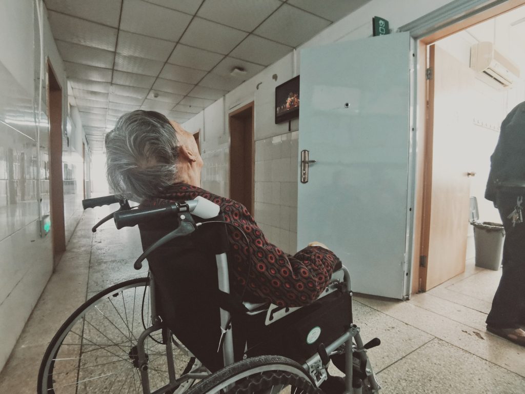 elderly woman in wheelchair in hospital hallway