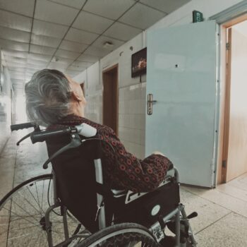 elderly woman in wheelchair in hospital hallway