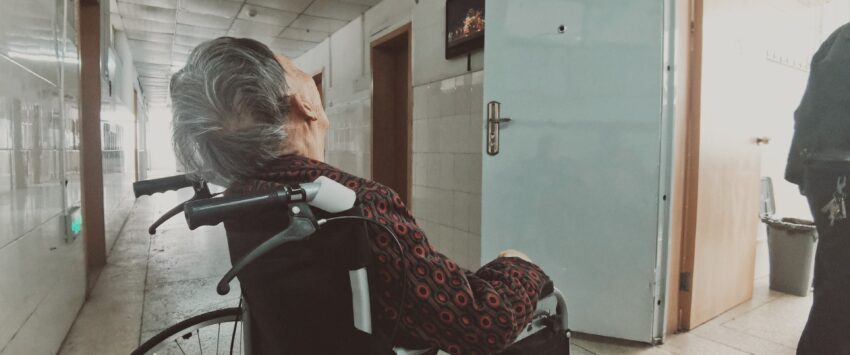 elderly woman in wheelchair in hospital hallway