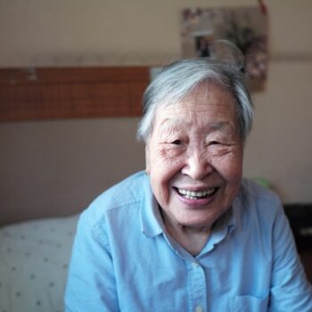 smiling elderly woman sitting on a bed