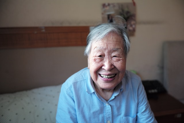 smiling elderly woman sitting on a bed