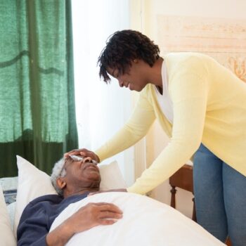 woman in cardigan helping elderly man