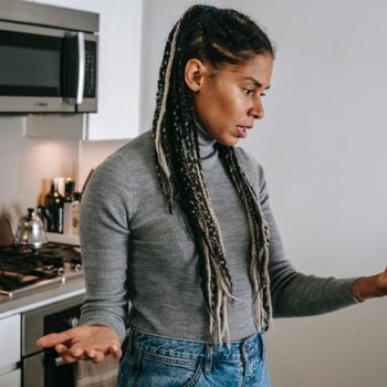 woman making annoyed gesture looking at phone in kitchen