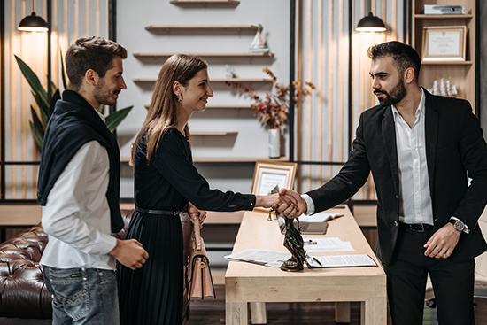 woman standing next to man shaking hands with man across the table