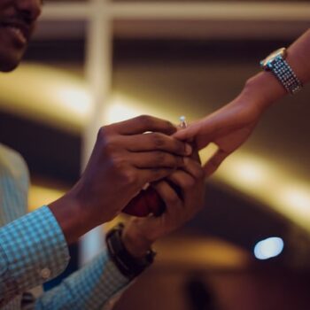 man putting ring on woman's finger