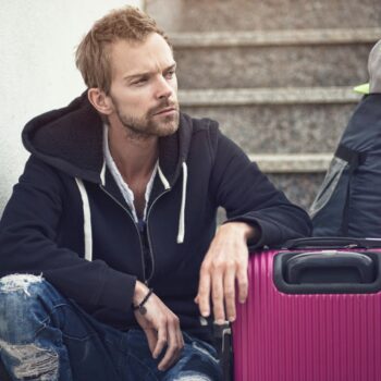 man with luggage sitting on stairs