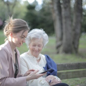 caregiver on park bench with elderly woman