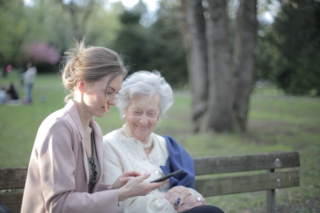 caregiver on park bench with elderly woman