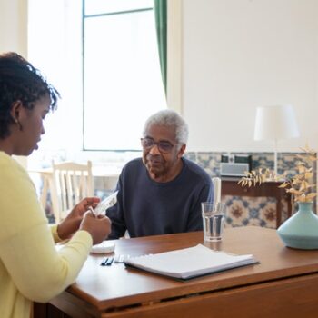 caregiver helping elderly man with medication