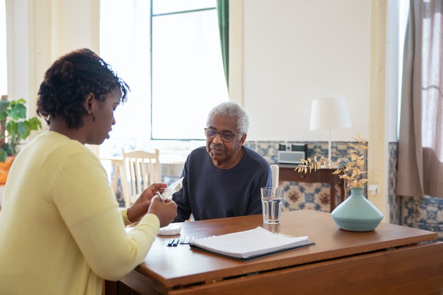 caregiver helping elderly man with medication