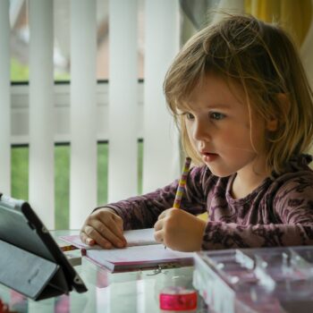 child writing in journal at tablet