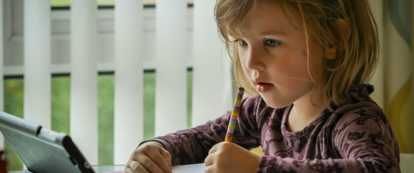 child writing in journal at tablet