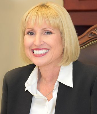Ann Marie Gilden smiling, sitting in desk chair